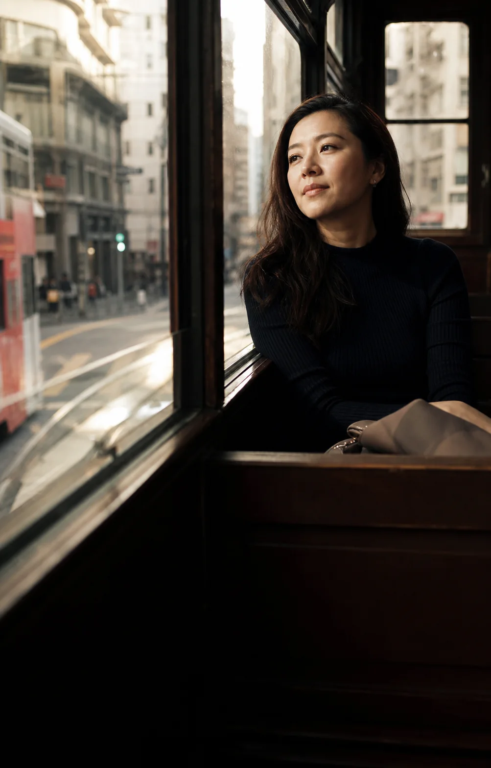 A Hong Kong woman looks through a tram window; a brand scene, not a real member.